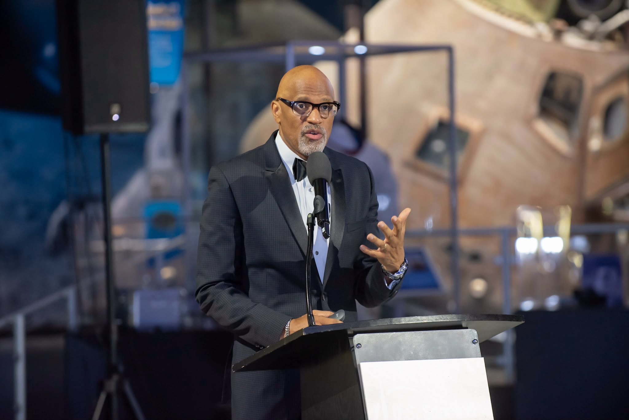 Dr. Nos speaking at a lectern