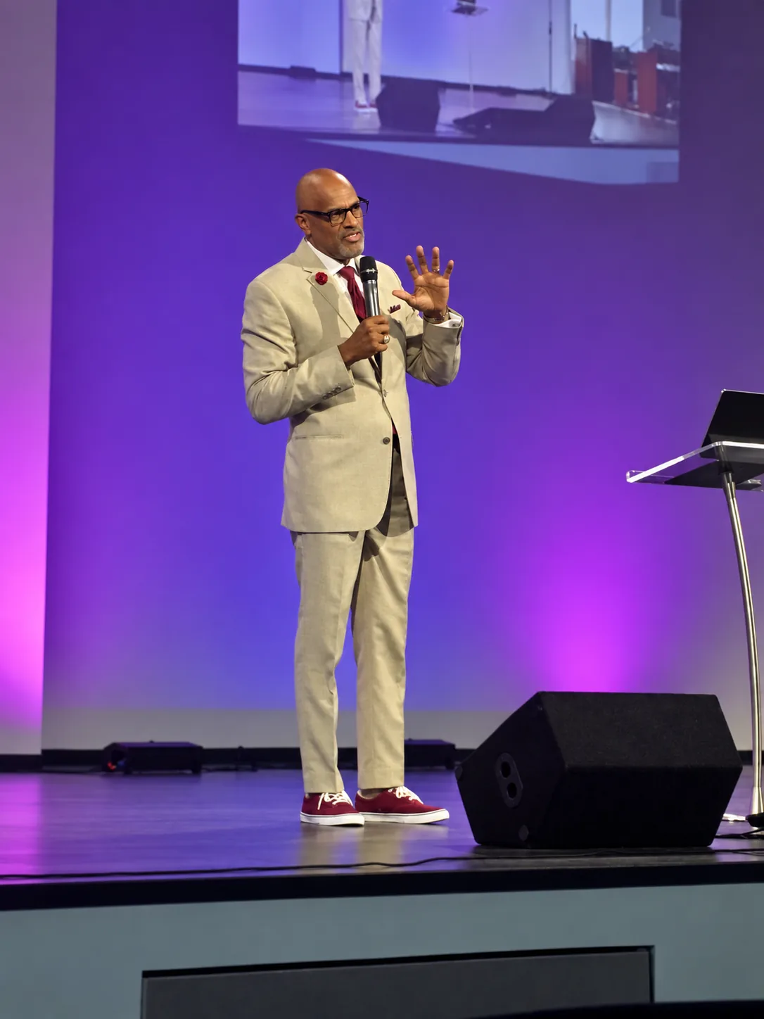 Dr. Nos speaking on a purple-lit stage